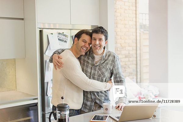 Portrait liebevolle männliche Homosexuell Paar Umarmung am Laptop in der Küche