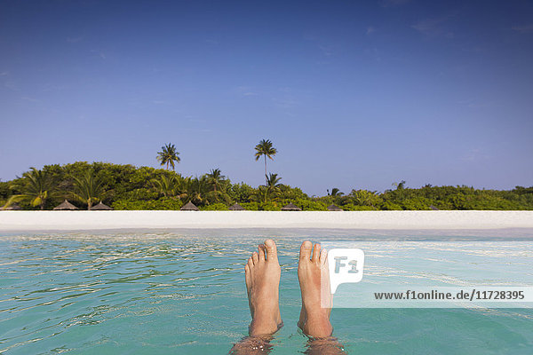 Persönliche Perspektive barfuß Mann schwimmt in tropischen Ozean mit Blick auf den Strand