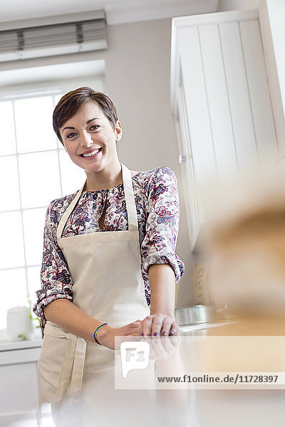 Portrait smiling brunette woman in apron in kitchen