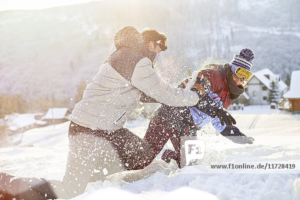 Verspieltes Paar genießt Schneeballschlacht im Schneefeld