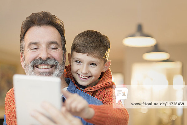 Vater und Sohn verbinden sich und teilen sich ein digitales Tablett.