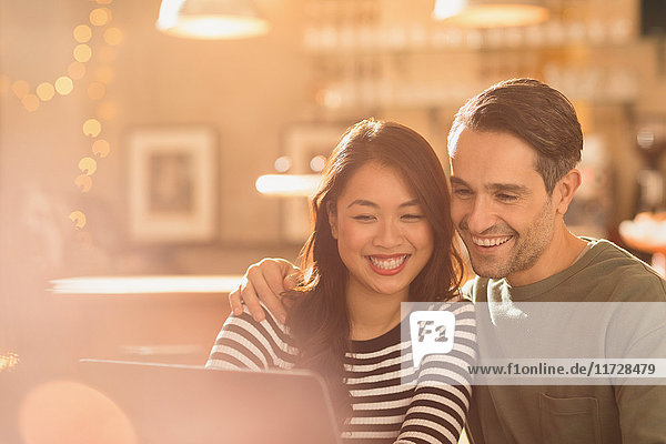 Lächelndes Paar beim Videochat am Laptop im Café