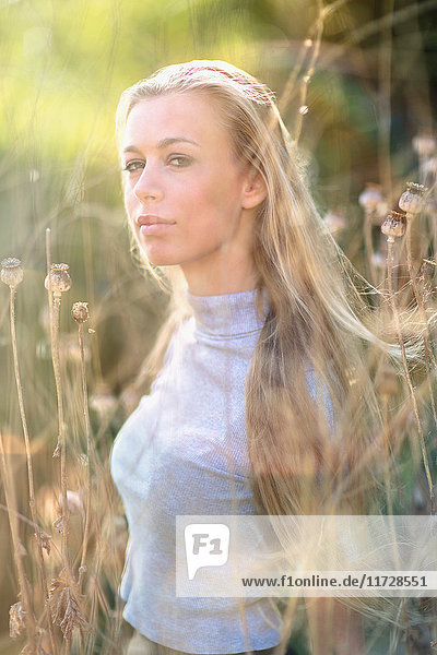 Porträt selbstbewusstes schönes blondes Teenager-Mädchen im hohen Gras