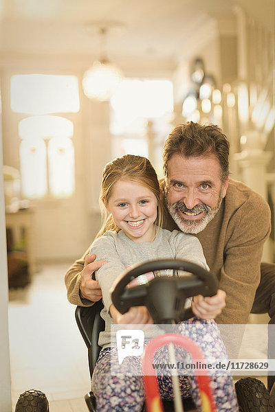 Porträt lächelnder Vater und Tochter beim Spielen mit dem Spielzeugauto