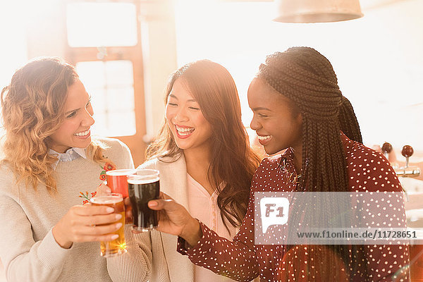 Women friends toasting beer glasses in bar