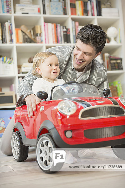 Vater schiebt Baby-Sohn im Spielzeugauto