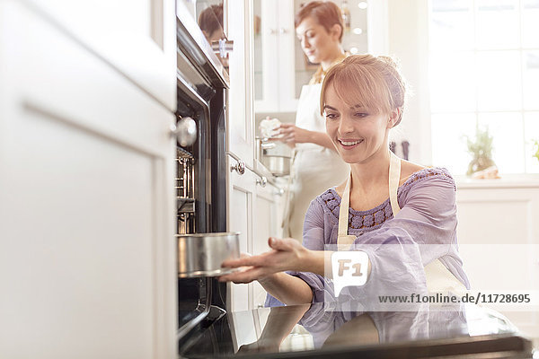Smiling woman baking  placing cake in oven