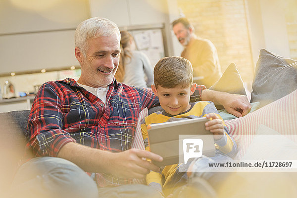 Vater und Sohn verbinden  mit digitalem Tablett auf dem Sofa
