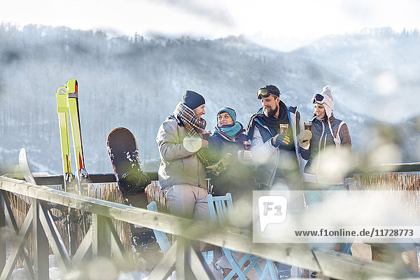 Skifahrerfreunde beim Reden und Trinken von Cocktails auf dem sonnigen Balkon Apres-Ski
