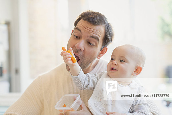 Babysohn füttert Vater mit Karotten