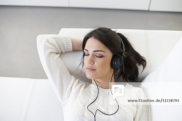 Pretty woman with headphones on the sofa