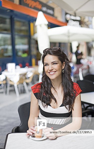 Porträt einer Frau bei einem Kaffee im Freien lächelnd