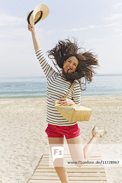 Young brunette woman jumping of happiness arriving at the beach