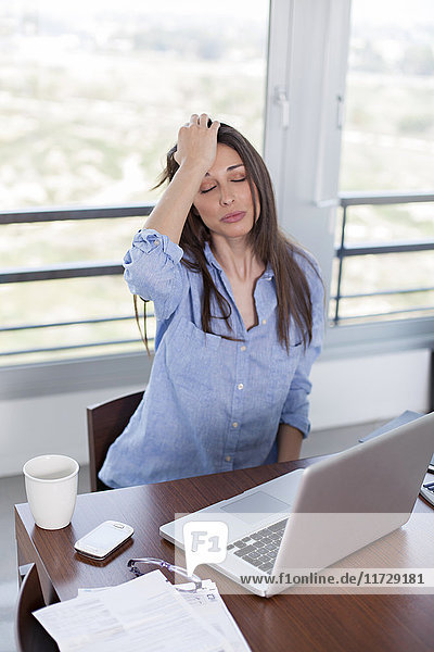 Frau mit Kopfschmerzen vor dem Computer