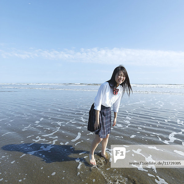 Young Japanese woman in a high school uniform running by the sea  Chiba  Japan