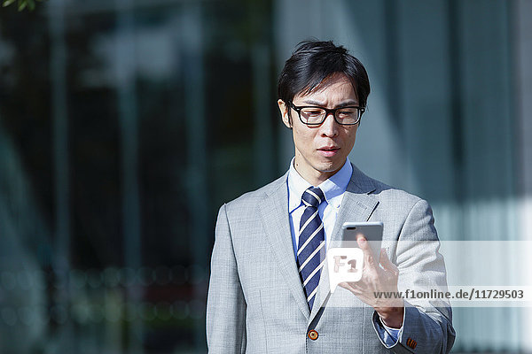 Japanese businessman with smartphone downtown Tokyo  Japan