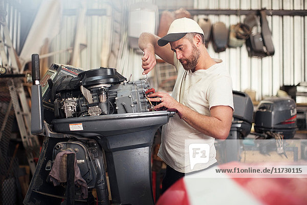 Mann repariert Außenbordmotor in Bootsreparaturwerkstatt