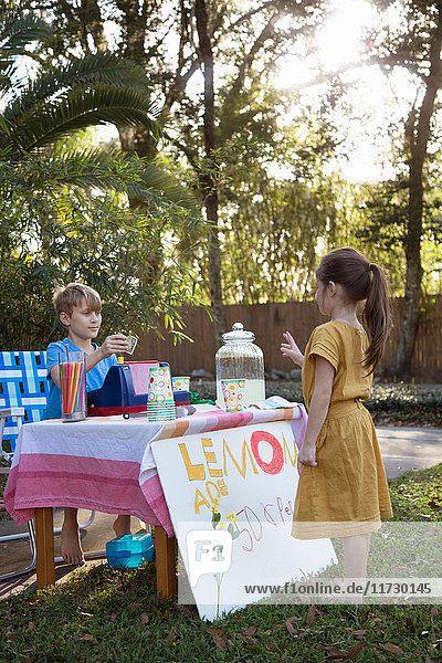 Mädchen kauft Limonade vom Limonadenstand im Garten