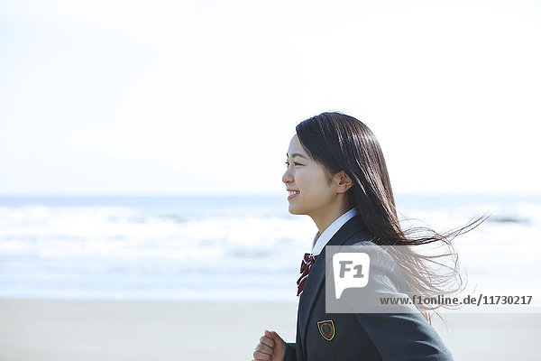 Young Japanese woman in a high school uniform running by the sea  Chiba  Japan