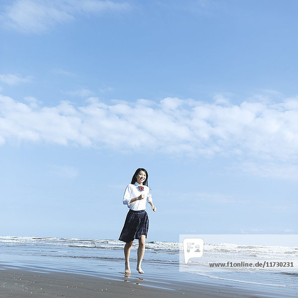 Junge Japanerin in Highschool-Uniform beim Laufen am Meer  Chiba  Japan