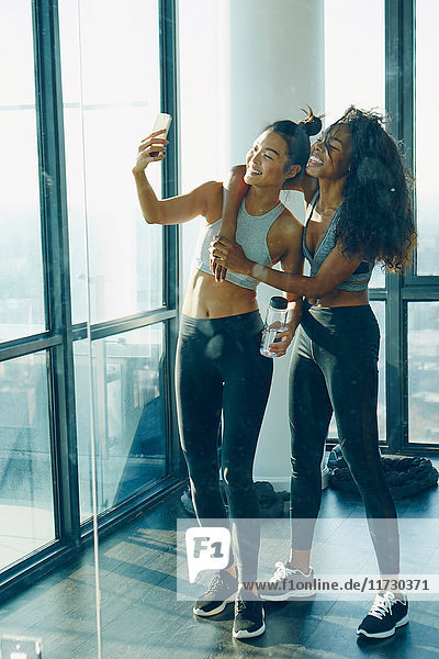 Zwei junge Frauen im Fitnessstudio  beim Selfie  mit Smartphone