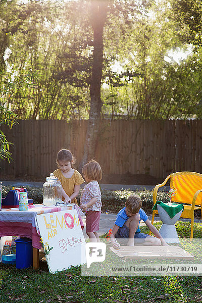 Junge und zwei junge Schwestern bereiten Limonadenstand im Garten vor