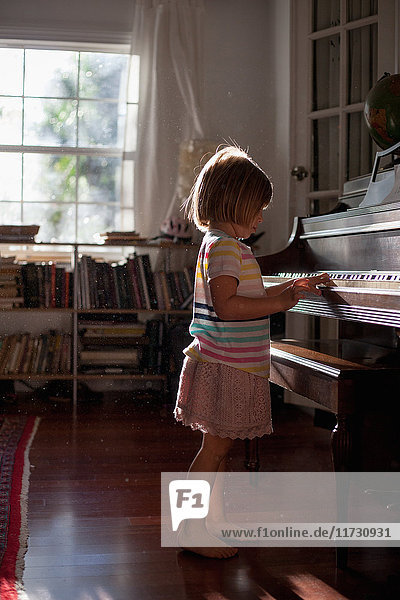 Girl standing playing old piano at home