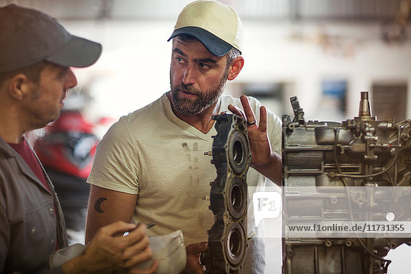 Two men repairing outboard motor in boat repair workshop