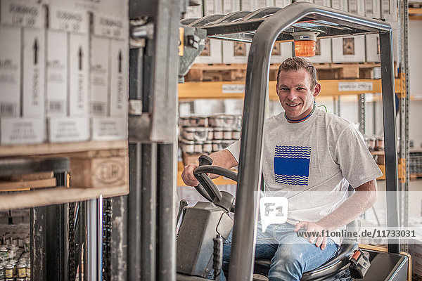 Portrait of young male forklift driver in factory warehouse