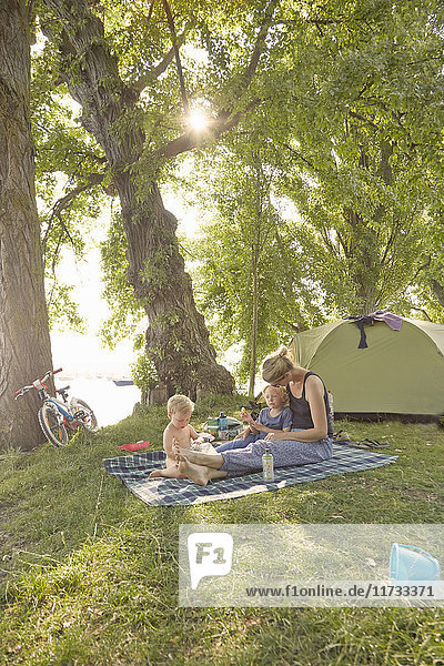 Mutter und Söhne entspannen sich auf einer Picknickdecke in ländlicher Umgebung
