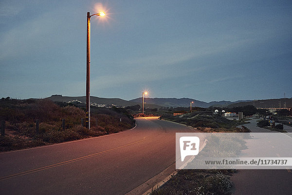 View of street lights on winding road at dusk