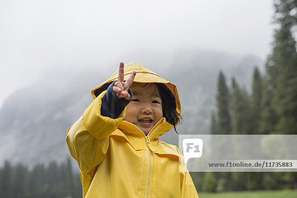 Porträt eines weiblichen Kleinkindes im gelben Regenmantel als Friedenszeichen  Yosemite National Park  Kalifornien  USA