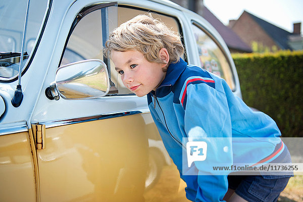 Junge schaut in den Außenspiegel eines Autos