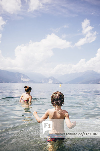 Rückansicht der Taille von Mutter und Sohn tief im See, Luino, Lombardei, Italien