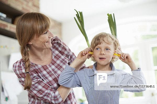 Mutter und Sohn spielen in der Küche mit Gemüse