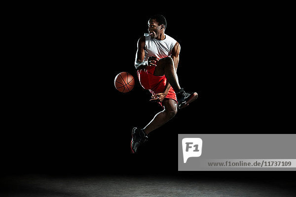 Junger männlicher Basketballspieler in der Luft
