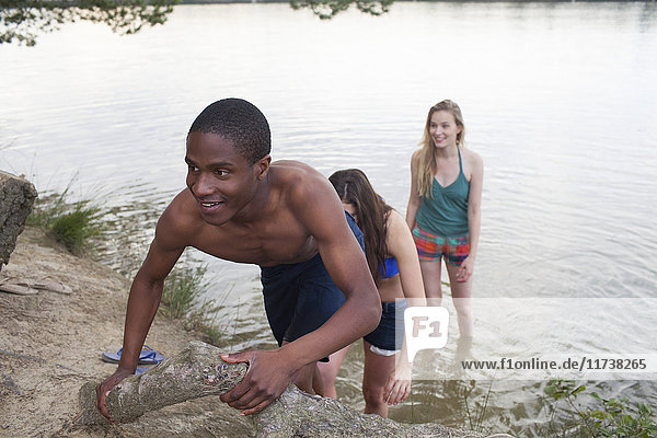 Friends climbing bank by lake