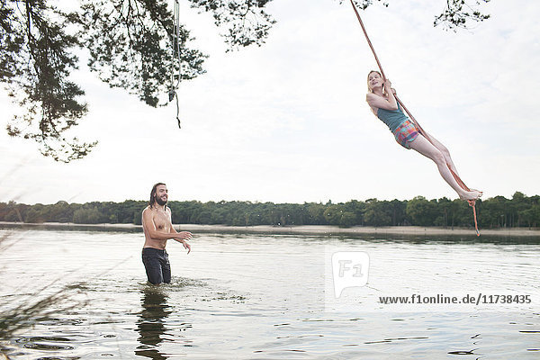Junge Frau schwingt Seil über dem See