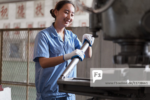 Fabrikarbeiterin schiebt Maschinenhebel in Kranfabrik China