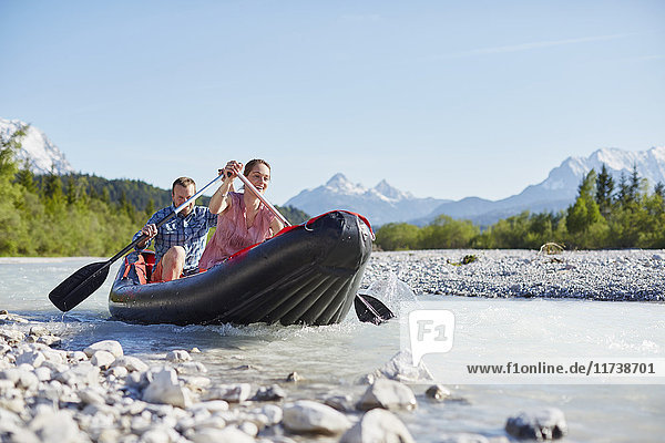 Ehepaar mit Paddel zum Steuern eines Beibootes auf dem Wasser  Wallgau  Bayern  Deutschland