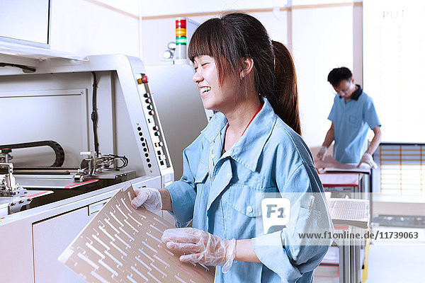 Junge Frau in Fertigungsanlage  die flexible Elektronik herstellt  lacht mit geschlossenen Augen