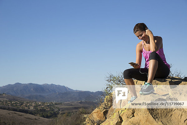 Läuferin wählt Smartphone-Musik auf dem Hügel  Thousand Oaks  Kalifornien  USA