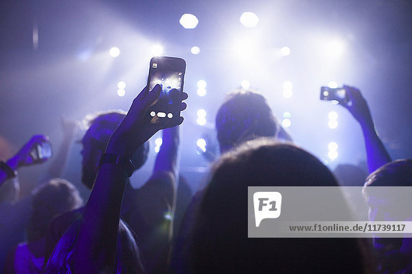 Group of friends watching and taking photograph of performer in club
