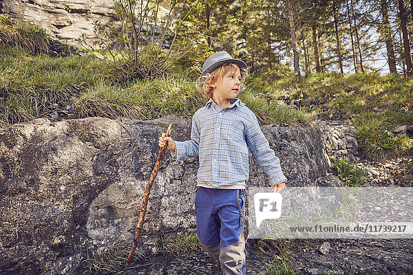 One young boy holding stick exploring forest