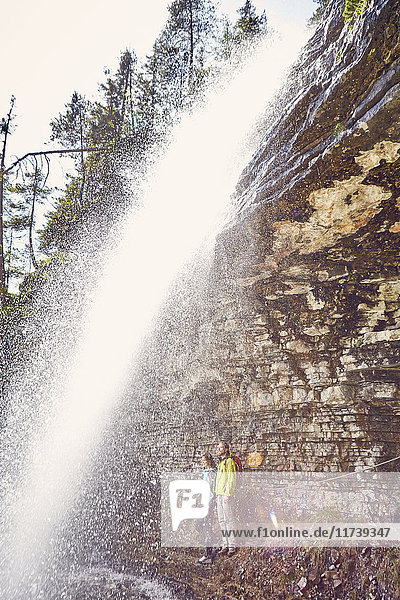 Junges Paar steht unter einem Wasserfall und schaut hinaus  Tirol  Österreich