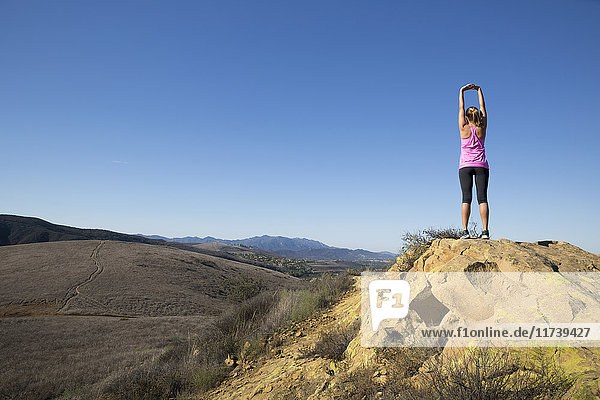 Rear view of woman practicing yoga pose on top of hill  Thousand Oaks  California  USA