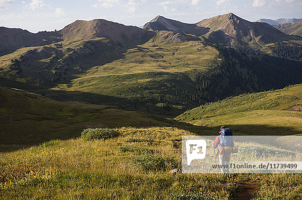 Woman hiking over Frigid Air Pass  West Elk Mountains  Colorado  USA