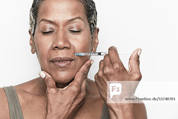 Senior woman injecting herself with botox