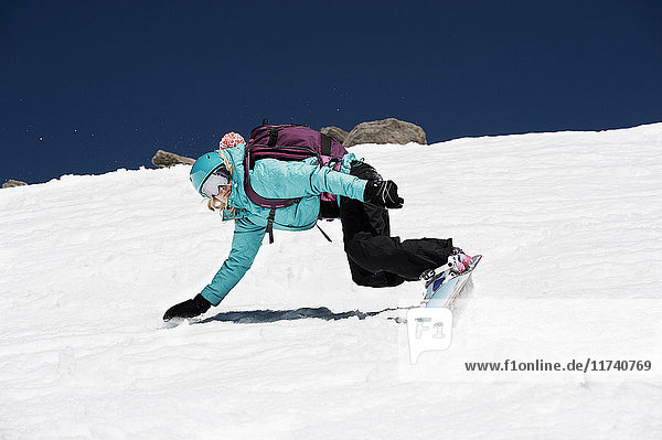 Weibliche Snowboarderin stürzt auf Berg