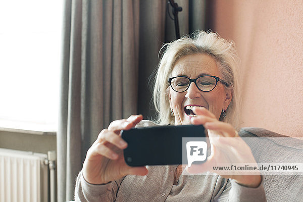 Ältere Frau  die ein Smartphone in der Hand hält  bei einem Videoanruf